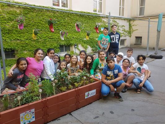 Gruppenbild der Kinder der VS Rötzergasse vor Hochbeeten im Schulhof