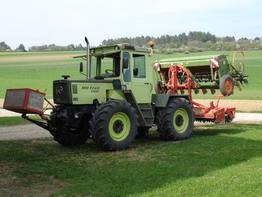 Grüner Tracktor mäht eine Wiese