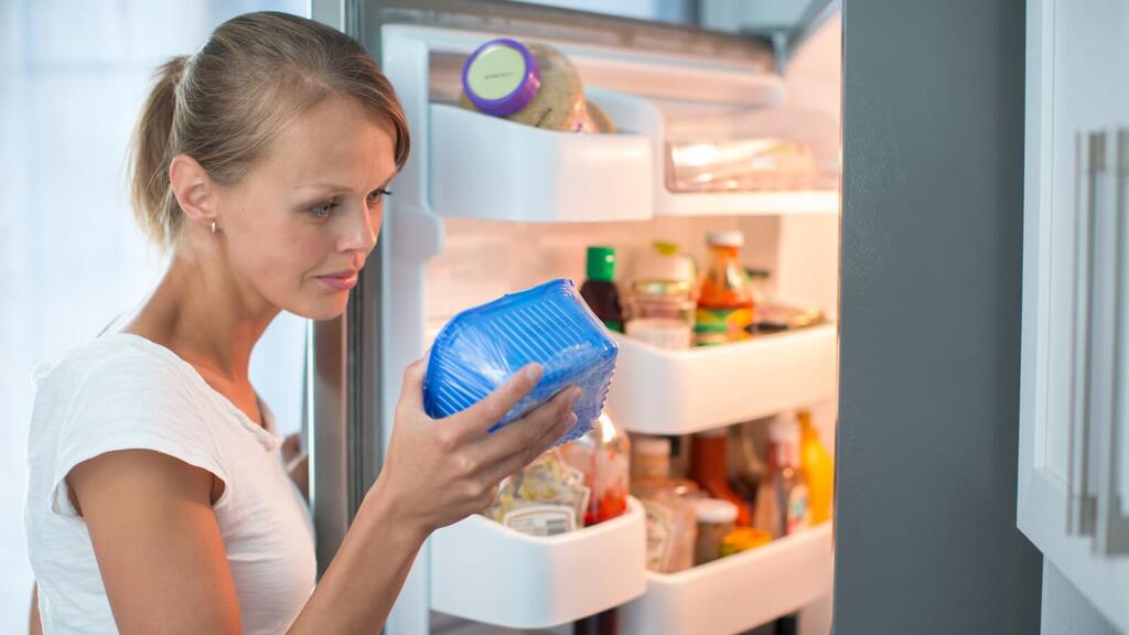 © iStock/ViktorCap/Thinkstock Frau mit Lebensmittel vor geöffnetem Kühlschrank