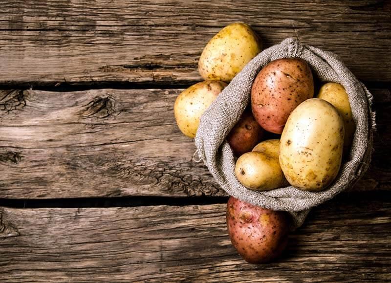 kartoffel_shutterstock_Artem-Shadrin © Artem Shadrin/Shutterstock.com Kartoffeln mit unterschiedlicher Schalenfarbe in Korb auf einem Holztisch
