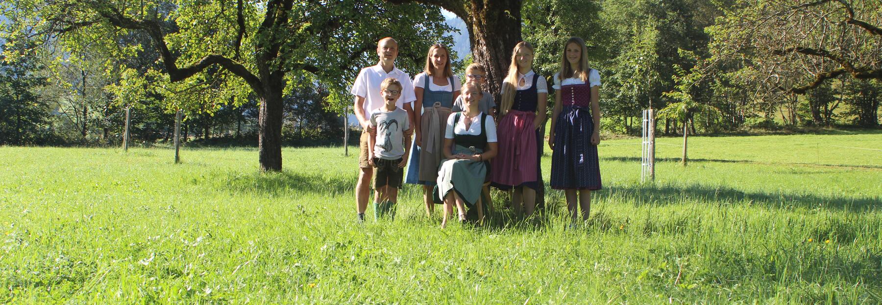 Eine Familie steht vor einem Apfelbaum 