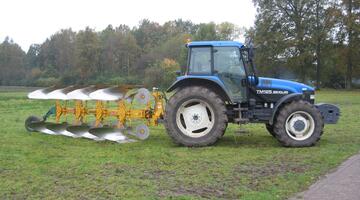 Blauer Tracktor mit einem Pflug